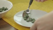 Nakładanie łyżeczką tabletek ze spiruliną na talerzyk