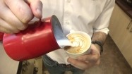 Barista robiący mleczne wzory na kawie