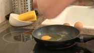 Wbijanie jajek na patelnię oraz szatkowanie ogórka i krojenie pomidora