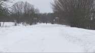 Człowiek idący zasypaną śniegiem drogą